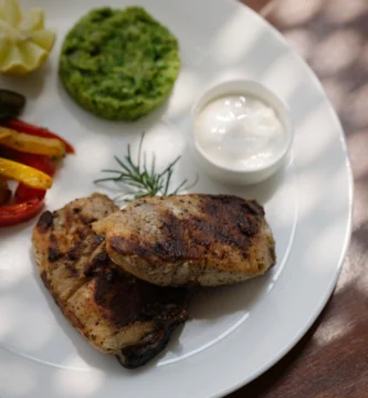 Plated grilled chicken dish with sides