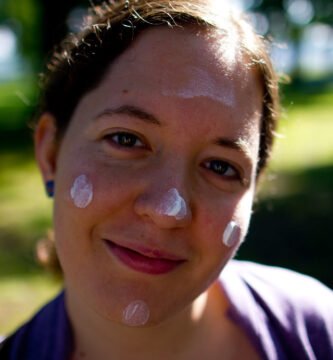 Person applying sunscreen to their face