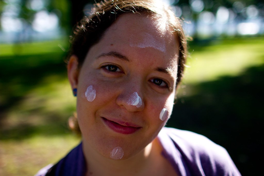 Person applying sunscreen to their face