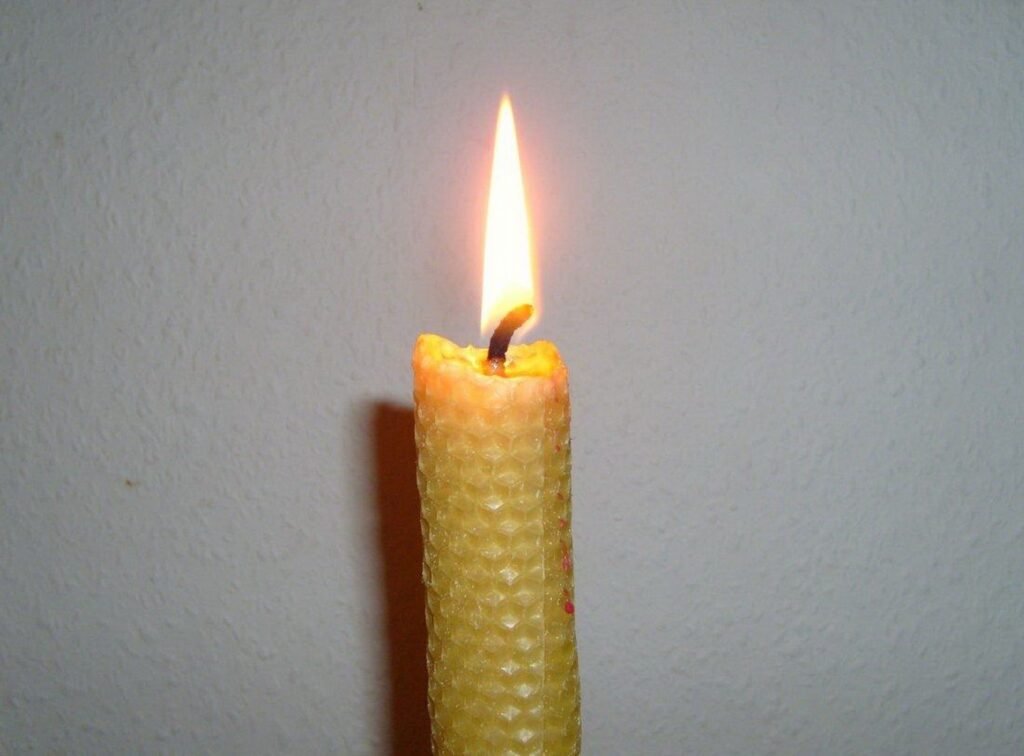Lit wax candle in a home setting